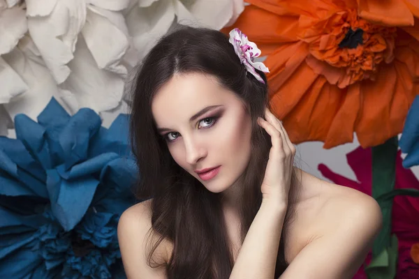 Beauty portrait of a model with a wreath of flowers on her head, holding a bouquet of roses and beautiful makeup — Stock Photo, Image