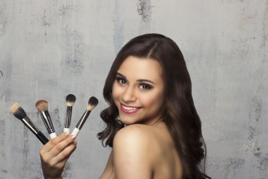 Güzel esmer makyaj uygulamak için bir fırça tutan