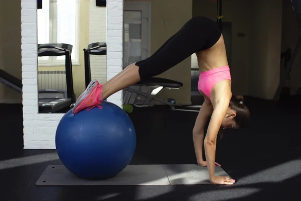 Beautiful girl fitness instructor demonstrates how to do the exercises in a gym with fitness Ball — Zdjęcie stockowe