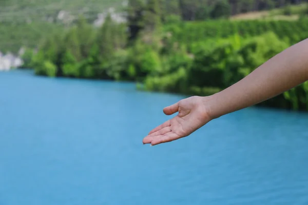 Ponto de mão mulher no lago azul — Fotografia de Stock