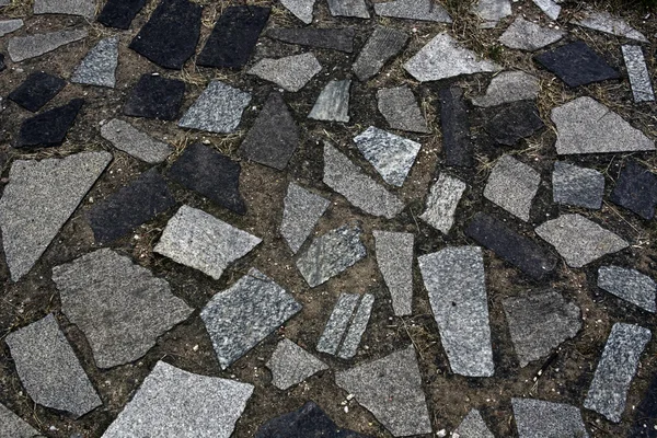 The texture of the ancient pavement of dark gray stones and ground — Stock Photo, Image