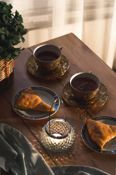 Çay saatinin samimi bir görüntüsü. Düz çay fincanları, tatlı turta ve mum. Sıcak çay partisi konsepti.