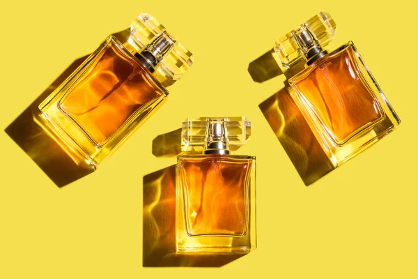 A pattern of woman perfume on the illuminating yellow background, top view, flat lay. Trend color of the year 2021. Mockup of fragrance perfume bottles