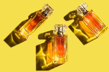 Aydınlatıcı sarı arka planda bir kadın parfümü deseni, üst manzara, düz yatış. 2021 yılının trend rengi. Parfüm şişelerinin maketi