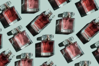 Turkuaz arka planda kadın parfümü şişeleri, üst manzara, düz yatak. Pembe parfüm şişesinin maketi turkuaz boş arkaplanda.