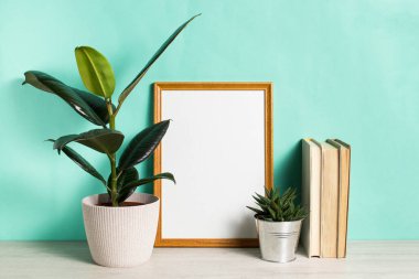 Kopyalama alanı olan bir poster. Bir kapsül içinde ev bitkisi, kaktüs ve İskandinav tarzı bir iç mekanda kitaplar. Turkuaz duvar, minimalizm.