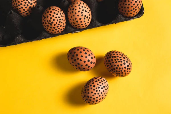 Yumurta kutusunda siyah noktalar olan boyanmış paskalya yumurtaları. Sarı yüzeydeki paskalya yumurtalarının en üst görüntüsü. Selamlama, davetiye ve kapak için maket. Paskalya düzlüğü. 2021 yılının trend rengi