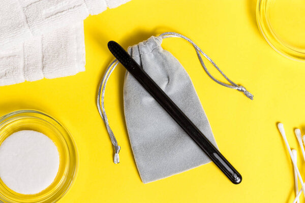 Black toothbrush on a grey sack on the yellow surface. Bath accessories. Trend colors of the year 2021.