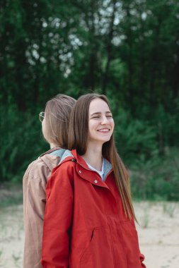 Sırt sırta verip gülen iki beyaz kadın arkadaş. Gerçek bir arkadaş ve destek konsepti 