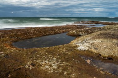 Arka planda deniz ve gökyüzü olan kaya havuzu