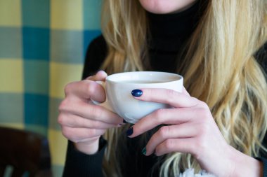 Bir kafede çay tutan sarışın kadın 