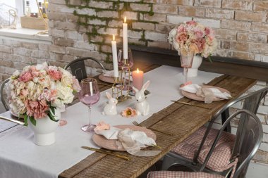 Romantik masa dekorunun, gözlüklü çiçeklerin ve mumların yan görüntüsü. Ahşap bir masada düğün Paskalya bayramı hazırlığı.