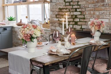 Gözlüklü çiçekler ve mumlarla süslü bir masa dekorunda yan görünüş. Bir mutfakta düğün Paskalya Bayramı tatili masası.