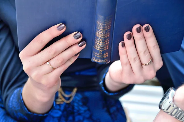 Mavi kitap nişan yüzüğü ile iki elle tutan kadın