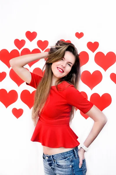 Λευκή καυκάσιος γυναίκα με κόκκινα χείλη στέκεται και να παίζουν με τα μαλλιά στην καρδιά σχήμα φόντου. Ημέρα του Αγίου Βαλεντίνου — Φωτογραφία Αρχείου