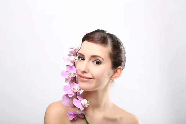 Menina bonita com flores da orquídea . — Fotografia de Stock