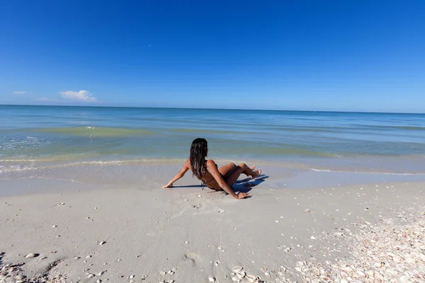 Kvinna sitter på stranden — Stockfoto