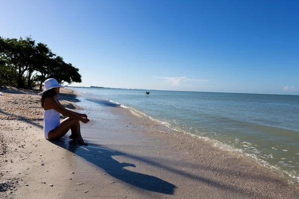 Kvinna sitter på stranden — Stockfoto