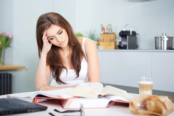 Joven estudiante con muchos libros estudiando — Foto de Stock