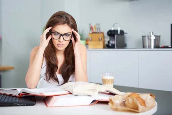 Happy young woman studying in kitchen — Stock Photo, Image