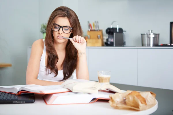 Happy young woman studying in kitchen — Stock Photo, Image