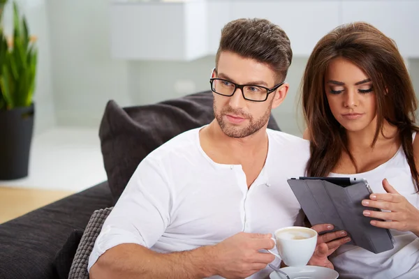 Mujer con tableta y marido leyendo periódico —  Fotos de Stock