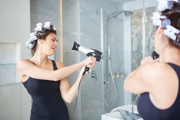 Junge Frau steckt Lockenwickler in ihr Haar, Badezimmer — Stockfoto