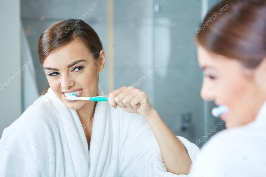 Young pretty woman brushing teeth