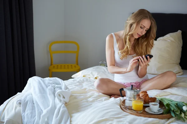 젊은 여 자가 침대에서 휴대 전화를 사용 하 여 — 스톡 사진