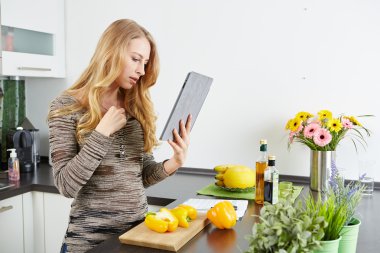 sarışın kadın pişirmek için bir tablet bilgisayar kullanma