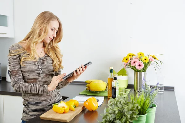 Mulher loira usando um computador tablet para cozinhar — Fotografia de Stock