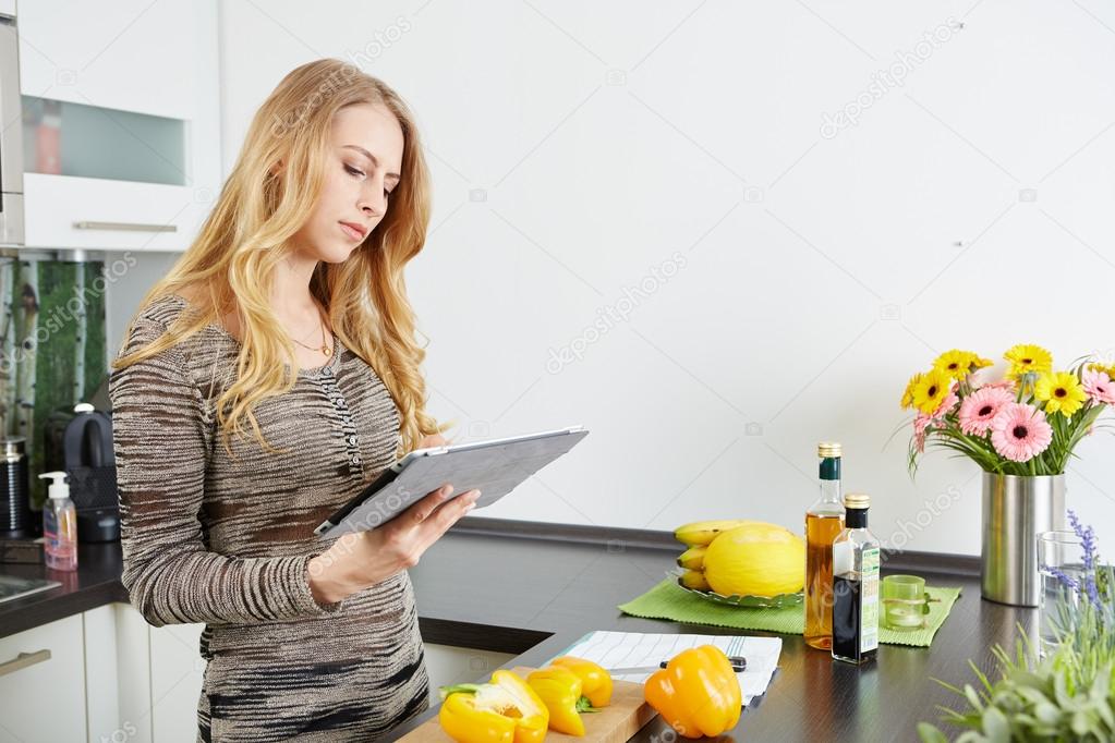 Blonde woman using a tablet computer to cook