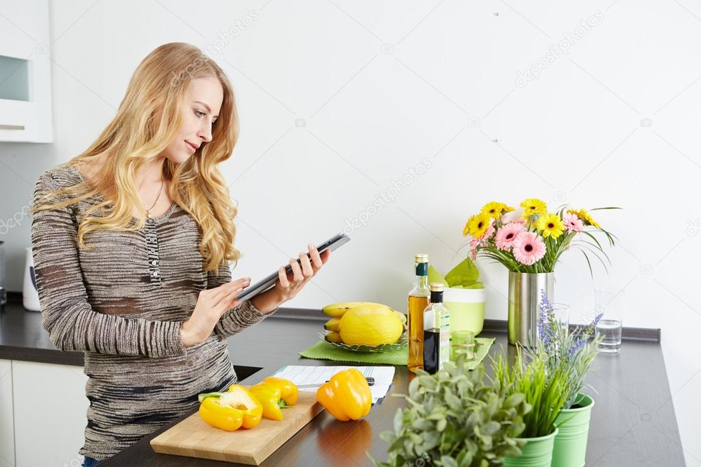 Blonde woman using a tablet computer to cook