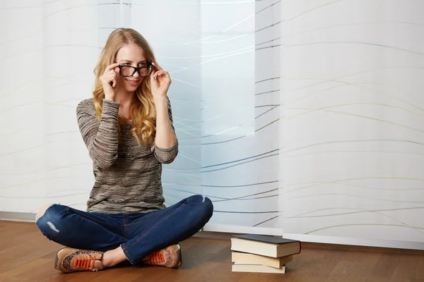 Flicka som läser en bok som sitter på golvet — Stockfoto