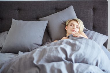 woman resting in bed with hands beside her head clipart