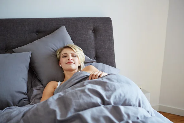 Kvinnan vila i sängen med händerna bredvid hennes huvud — Stockfoto