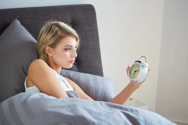 Surprised woman looking at alarm clock . — Stock Photo, Image