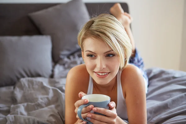 Happy smiling beautiful blond woman awaking with cup of coffee — Stock Photo, Image