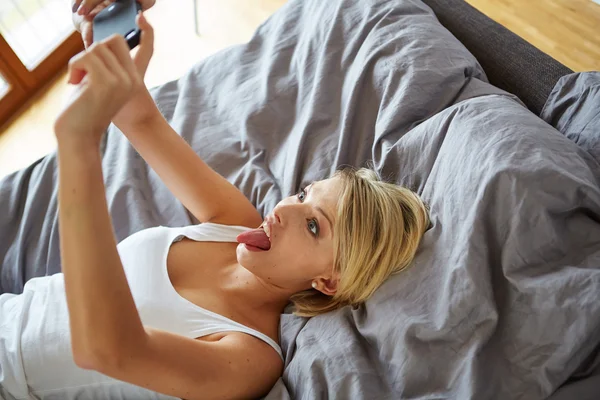 Mujer acostada en la cama y hacer una selfie — Foto de Stock