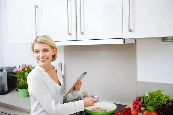 Mujer rubia usando una tableta para cocinar —  Fotos de Stock