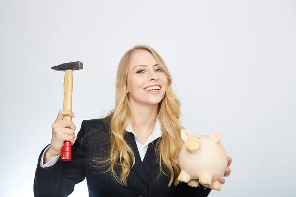 Ernstige zakenvrouw holding een spaarvarken en hamer — Stockfoto