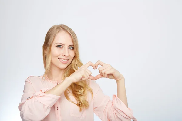 Jonge blonde vrouw maken van een hartsymbool — Stockfoto