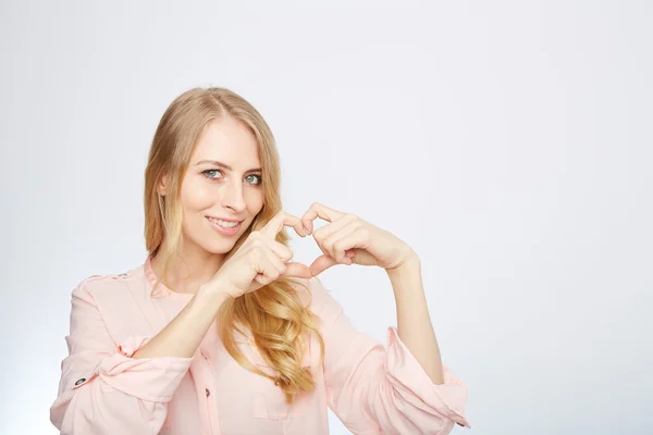 Jeune femme blonde faisant un symbole de coeur — Photo