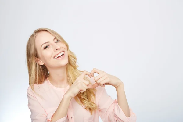 Jeune femme blonde faisant un symbole de coeur — Photo