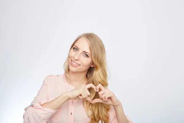 Jeune femme blonde faisant un symbole de coeur — Photo