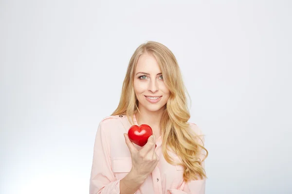 Joven rubia sosteniendo un corazón rojo. aislado en blanco . — Foto de Stock