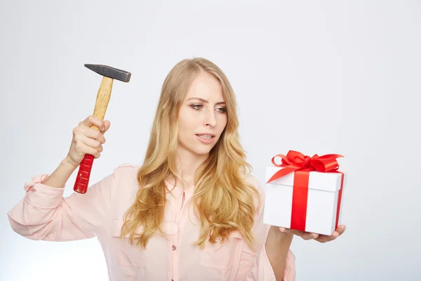 Young blond woman with present box and a hammer in her hand. — Stock Photo, Image
