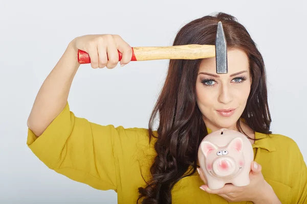 Jovem mulher esmagado porquinho banco com um martelo — Fotografia de Stock