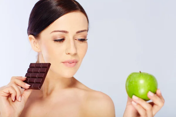 Жінка з яблуком і шоколадом в руці — стокове фото