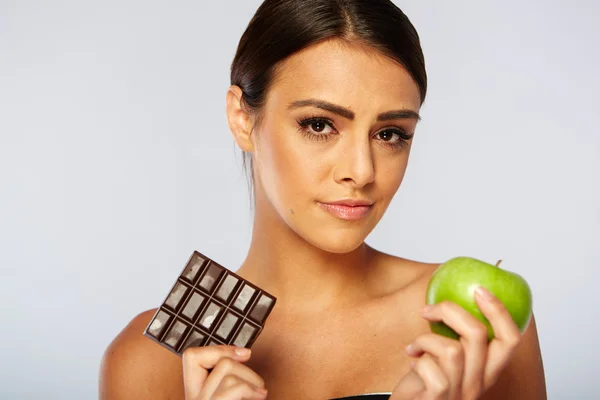 Donna sportiva che fa la scelta tra mela sana e cioccolato — Foto Stock